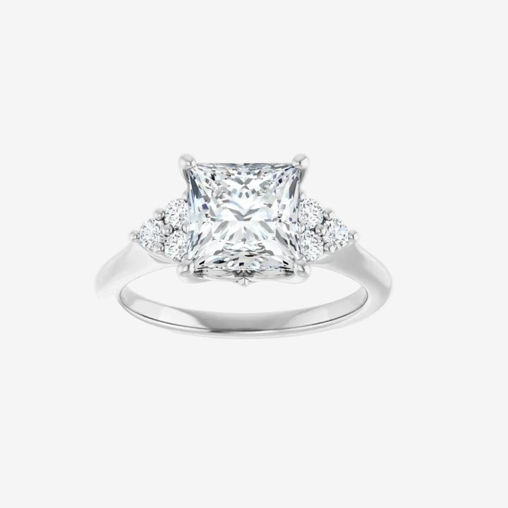 Diamond ring with a princess-cut center stone and round diamonds on the sides.